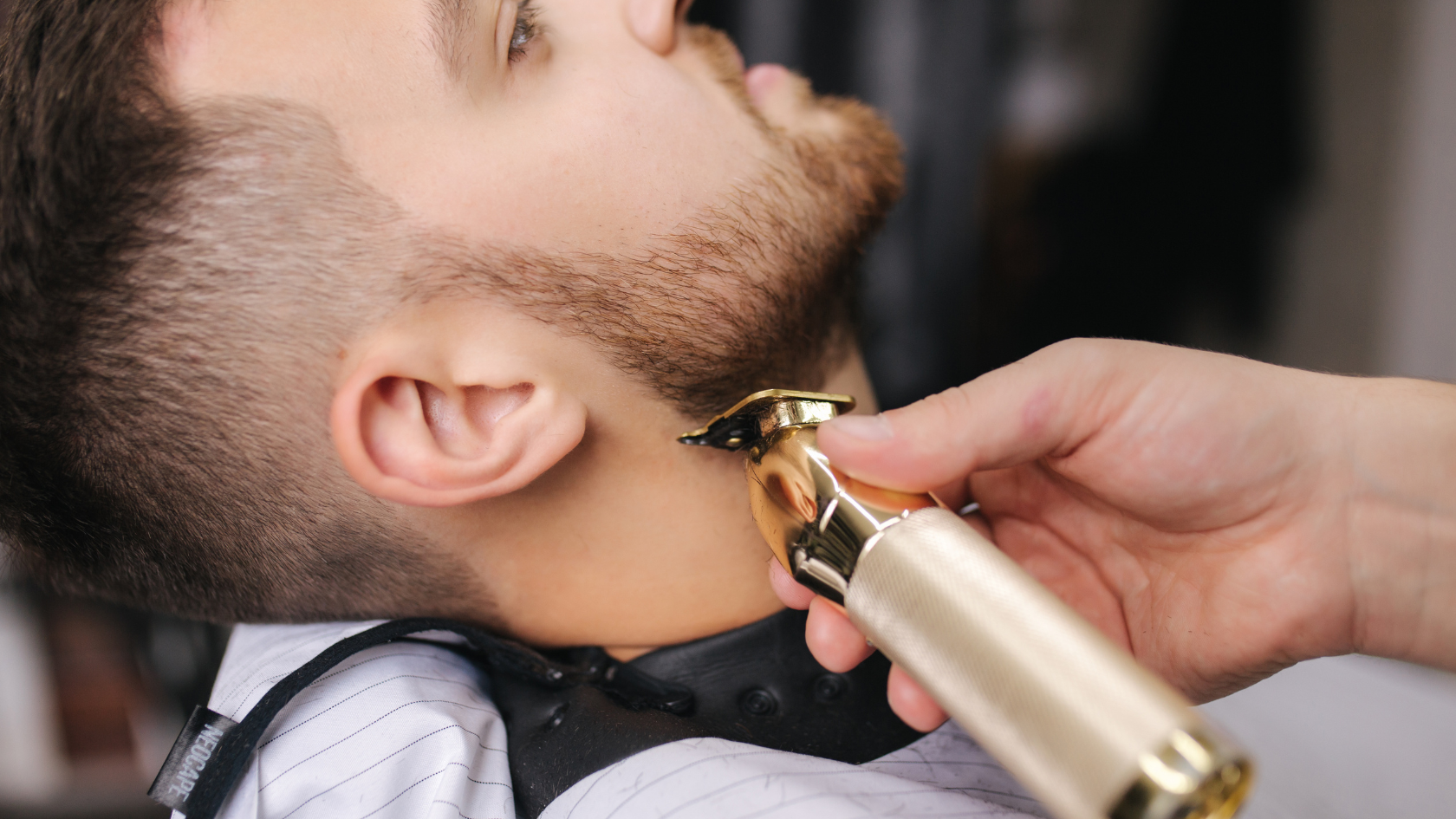 A man getting his hair cut with a gold trimmer